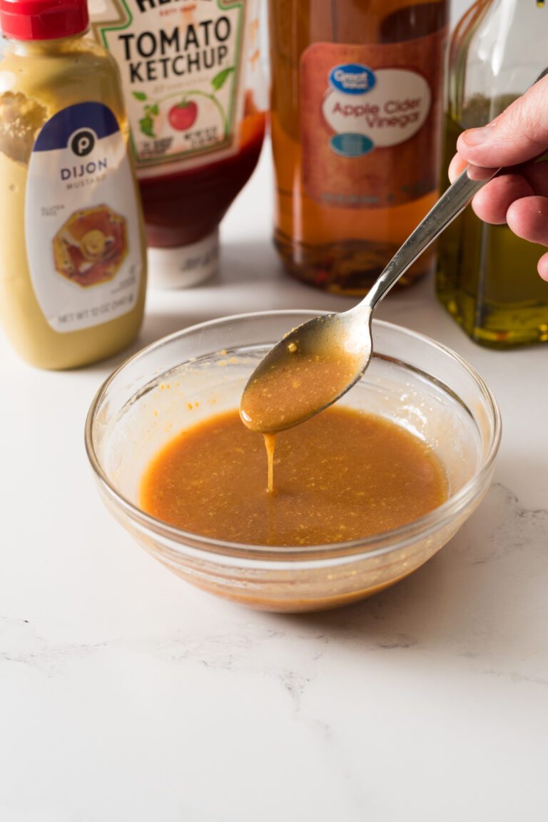 Meatloaf glaze with mustard in a glass bowl with a spoon.