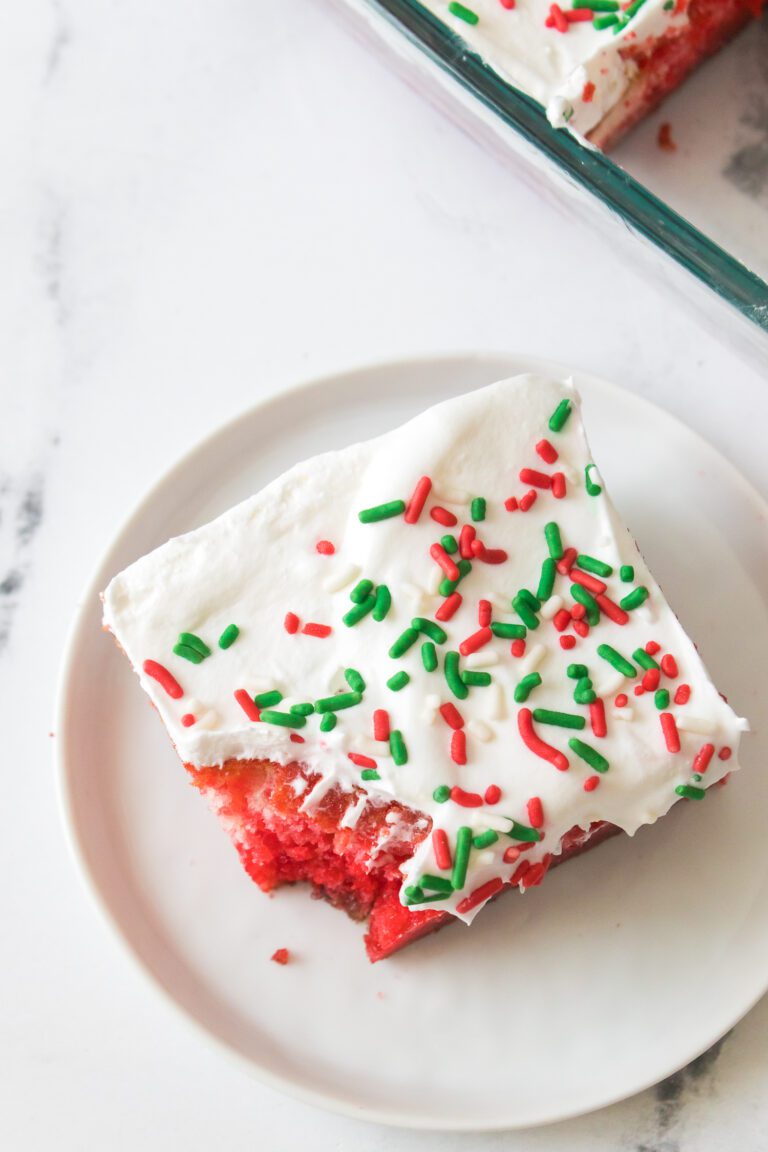 Traditional poke cake made with green and red jello with whipped topping and Christmas sprinkles